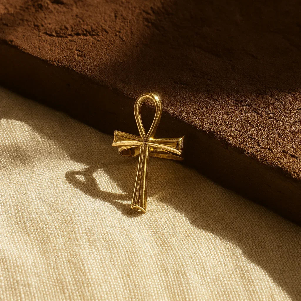 Gold ankh cross pendant on a textured brown surface