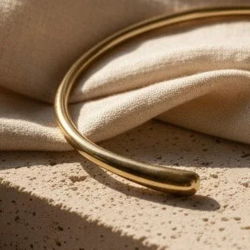 Gold bracelet on a textured beige surface