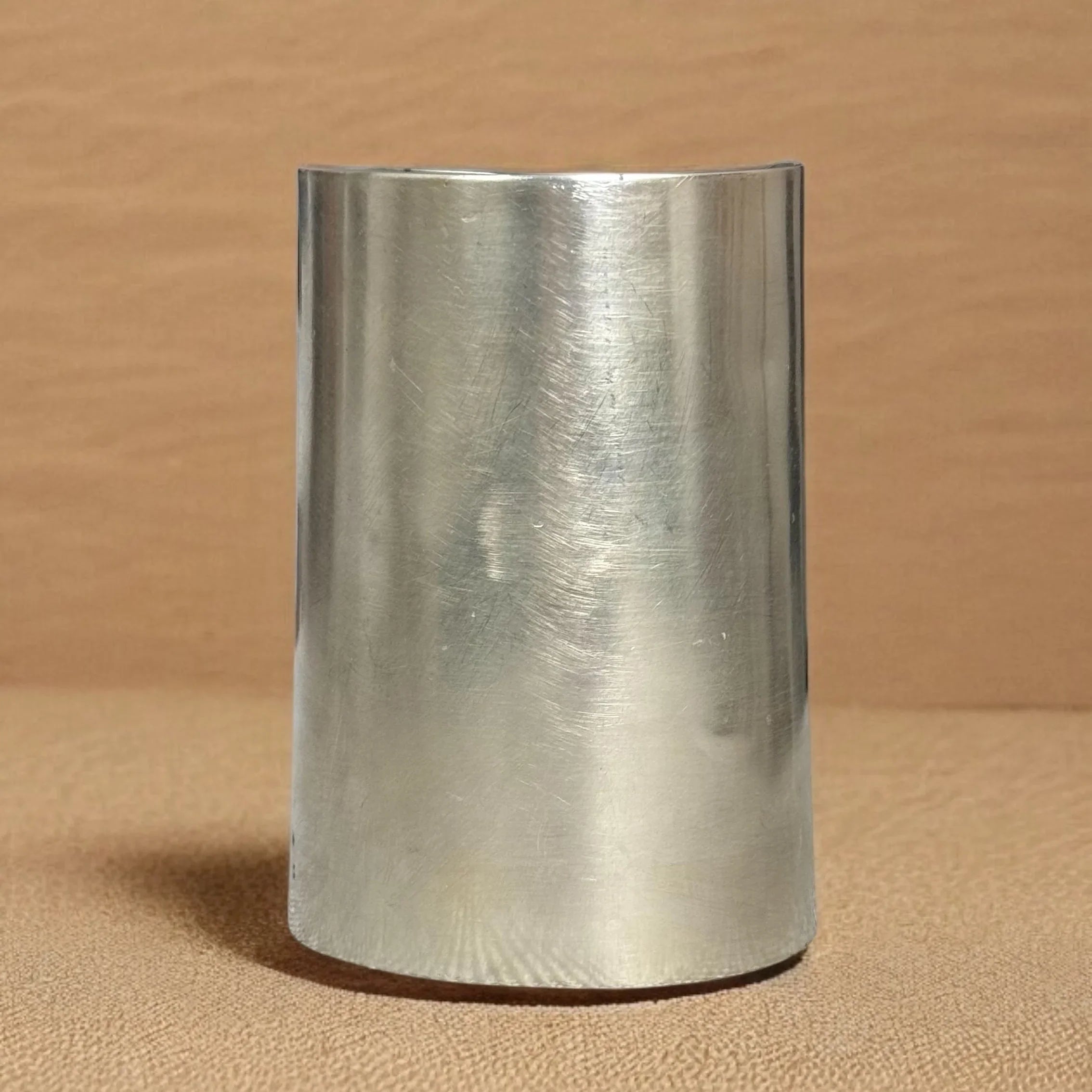 Metallic cylindrical object on a beige background