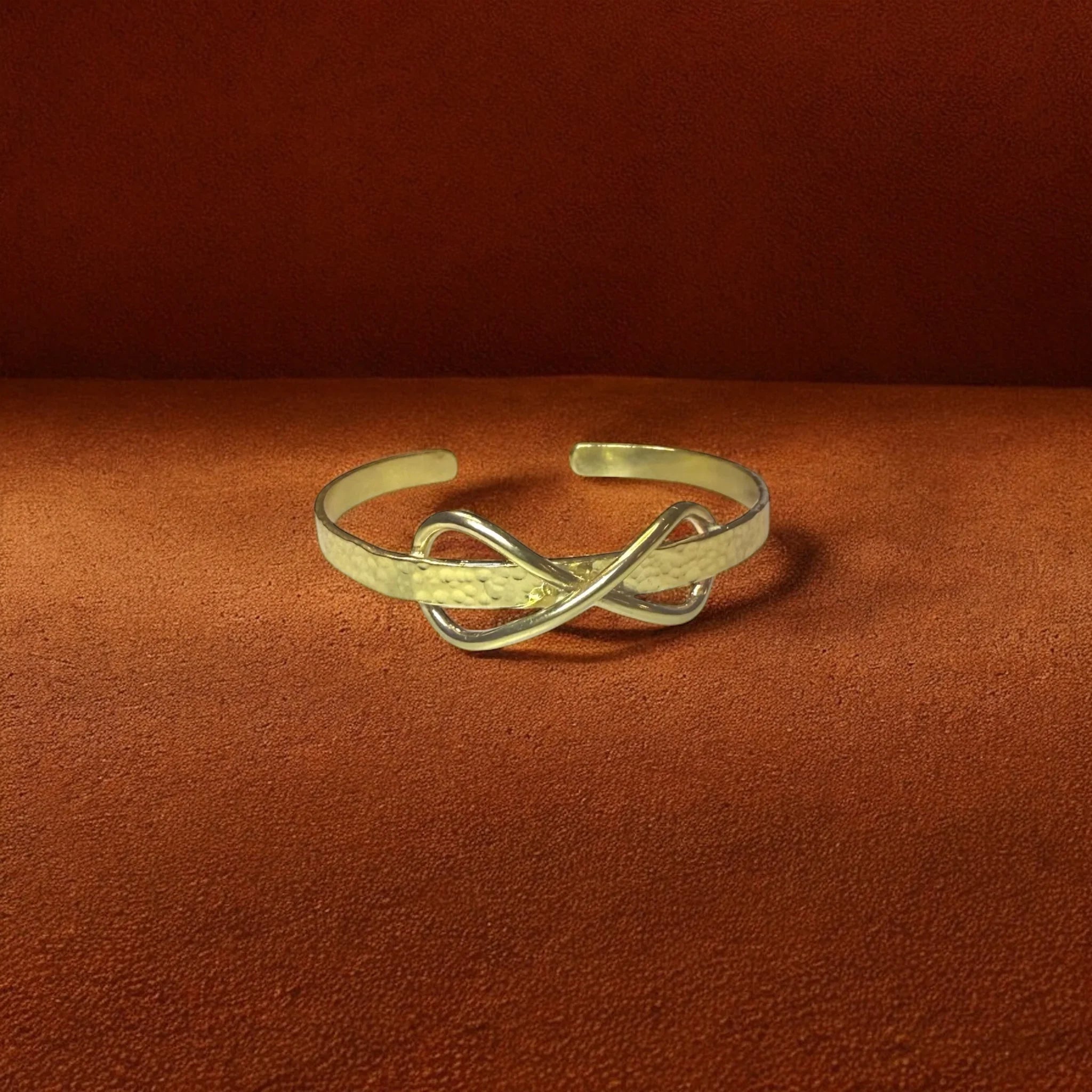Gold bracelet with an infinity design on a brown background