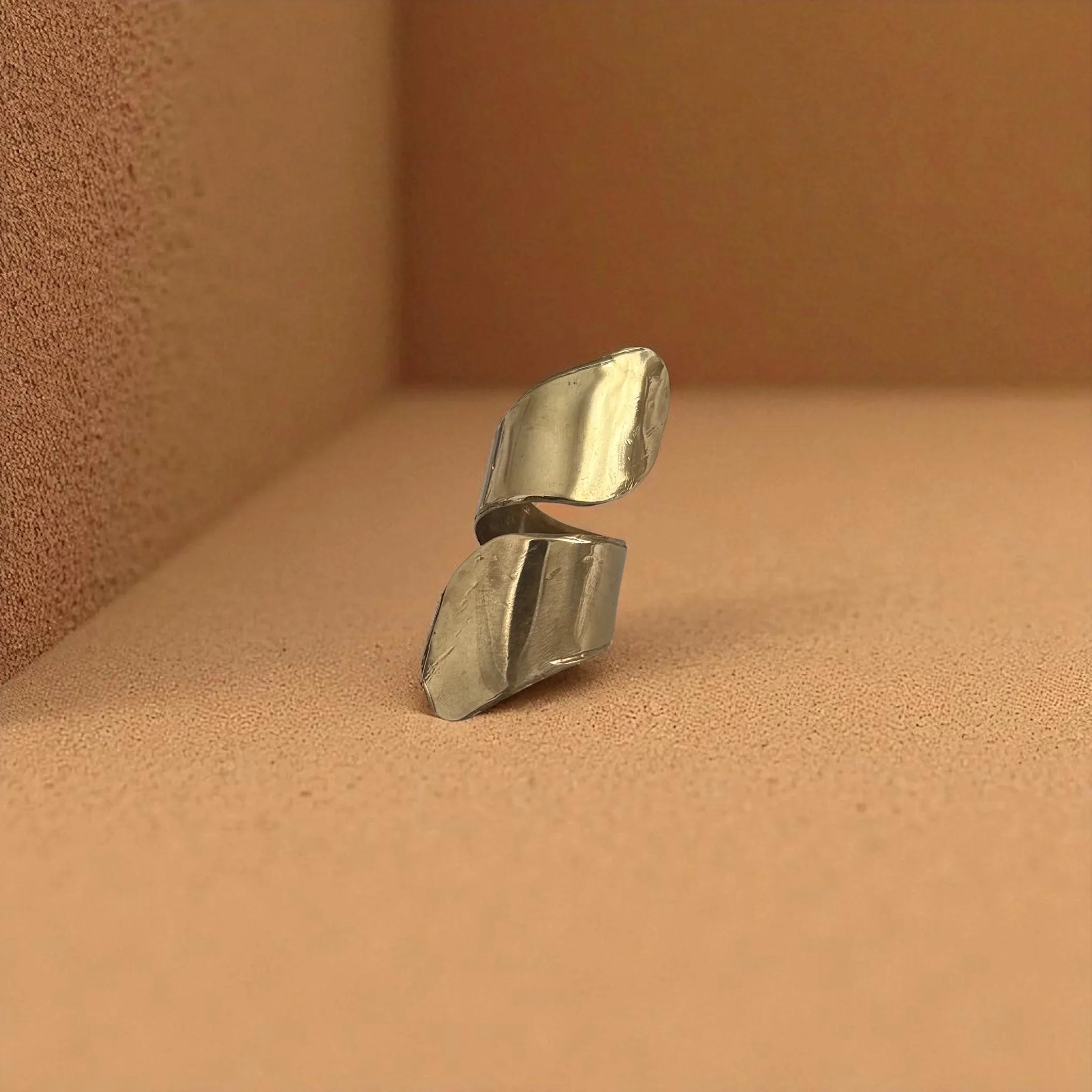 Silver ring with a textured design on a brown surface