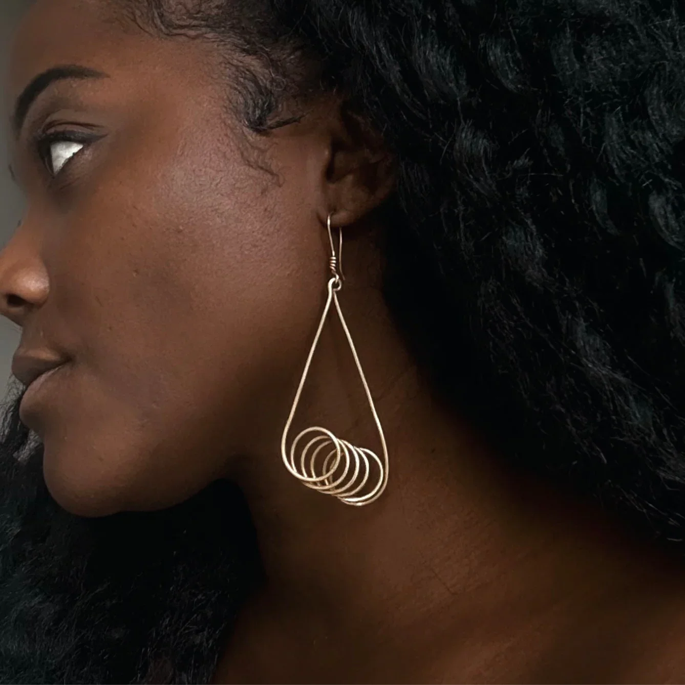 Close-up of a woman wearing a gold hoop earring with a dark background