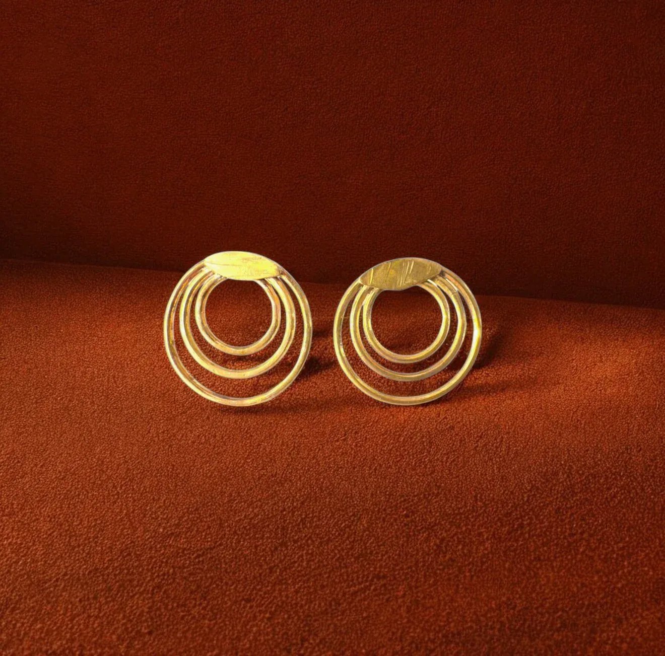 Pair of gold hoop earrings on a brown background