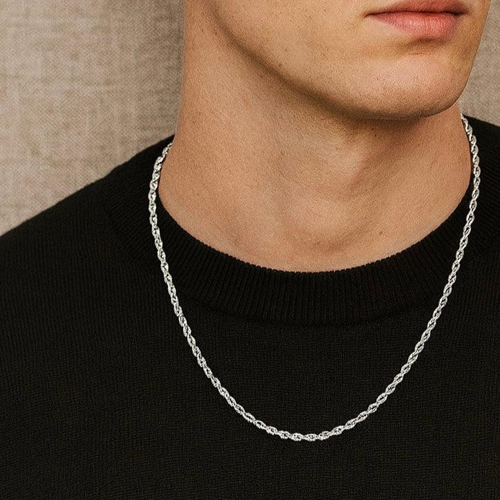 Person wearing a silver chain necklace against a neutral background
