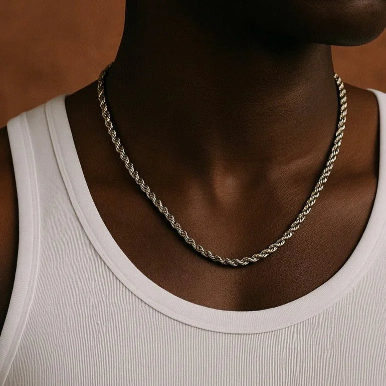 Person wearing a silver chain necklace against a neutral background