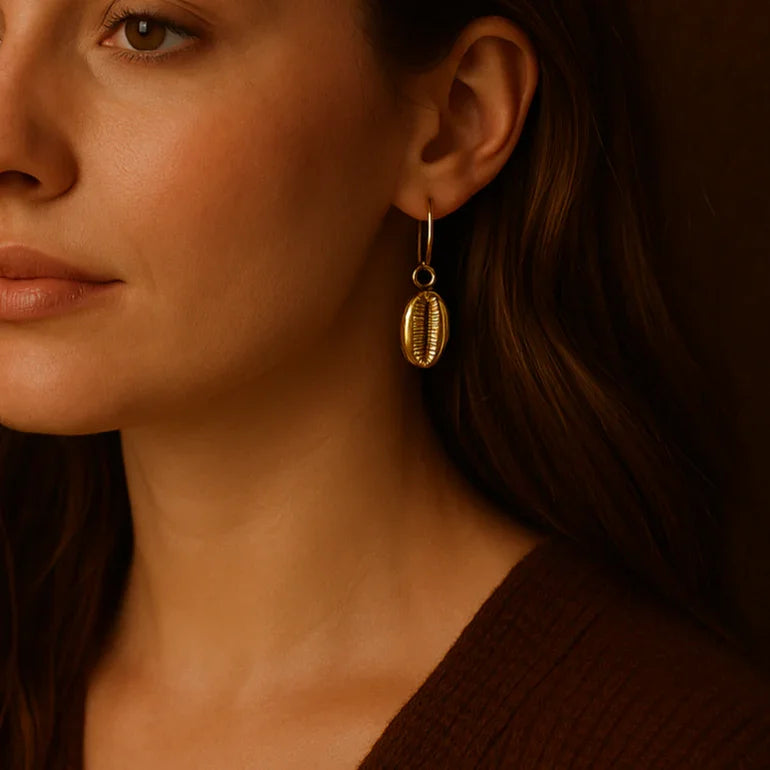 Woman wearing gold earrings against a brown background