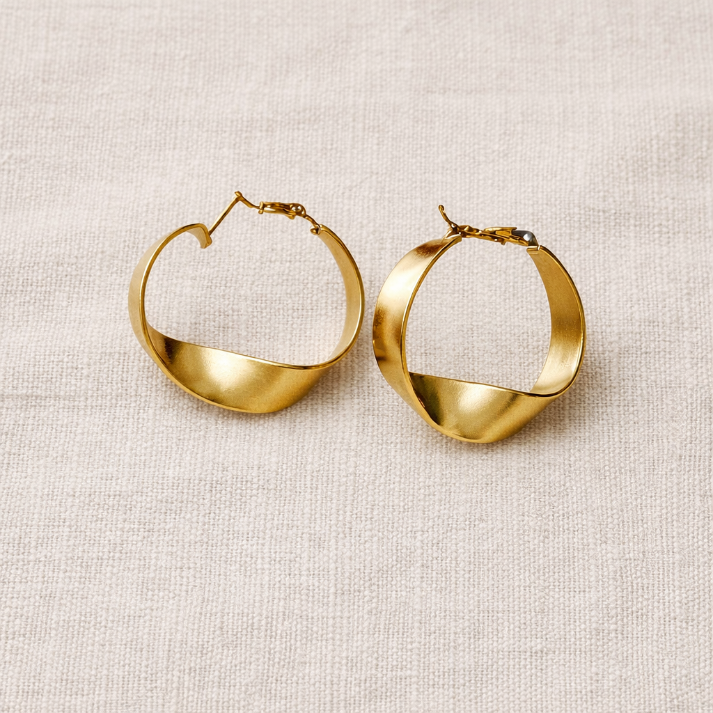 Gold hoop earrings on a beige fabric background