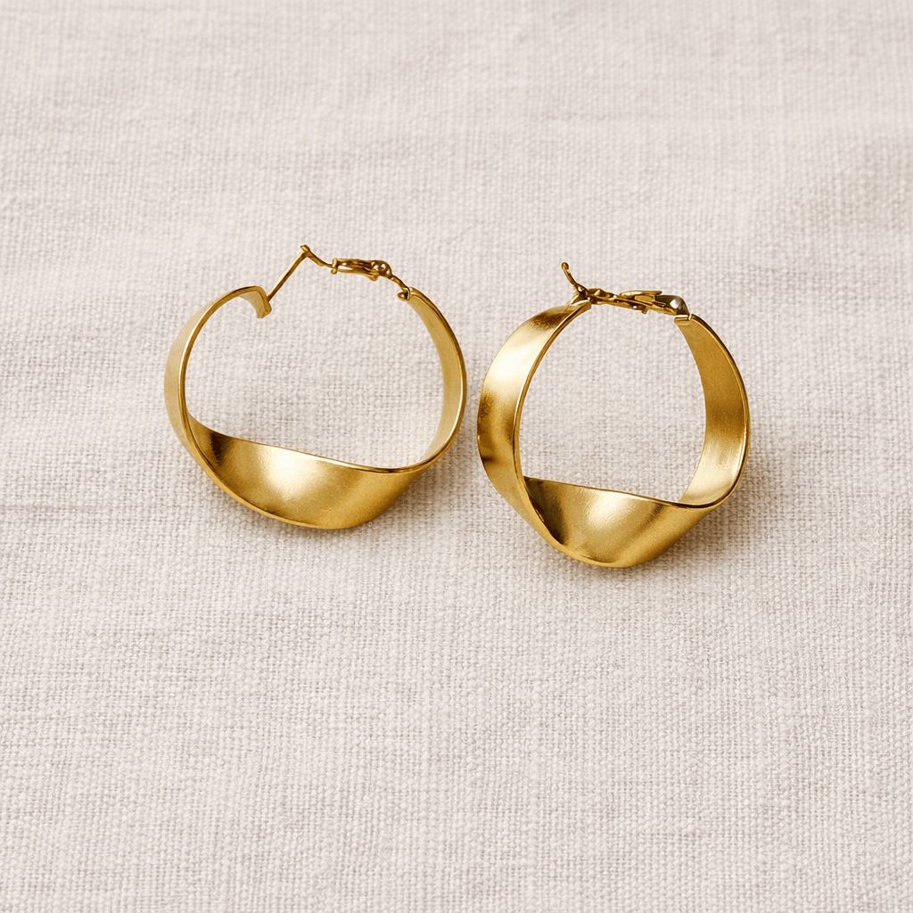 Gold hoop earrings on a beige fabric background