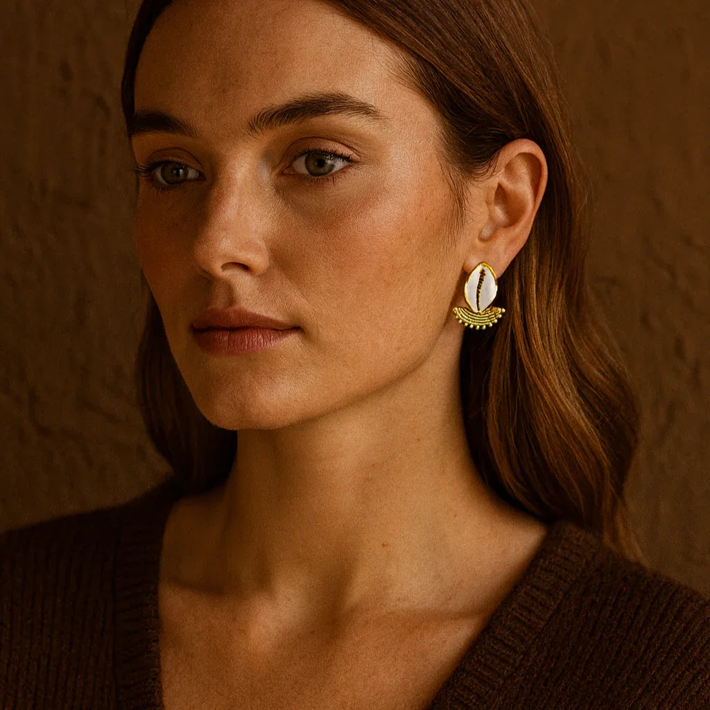 Woman wearing gold earrings against a warm brown background