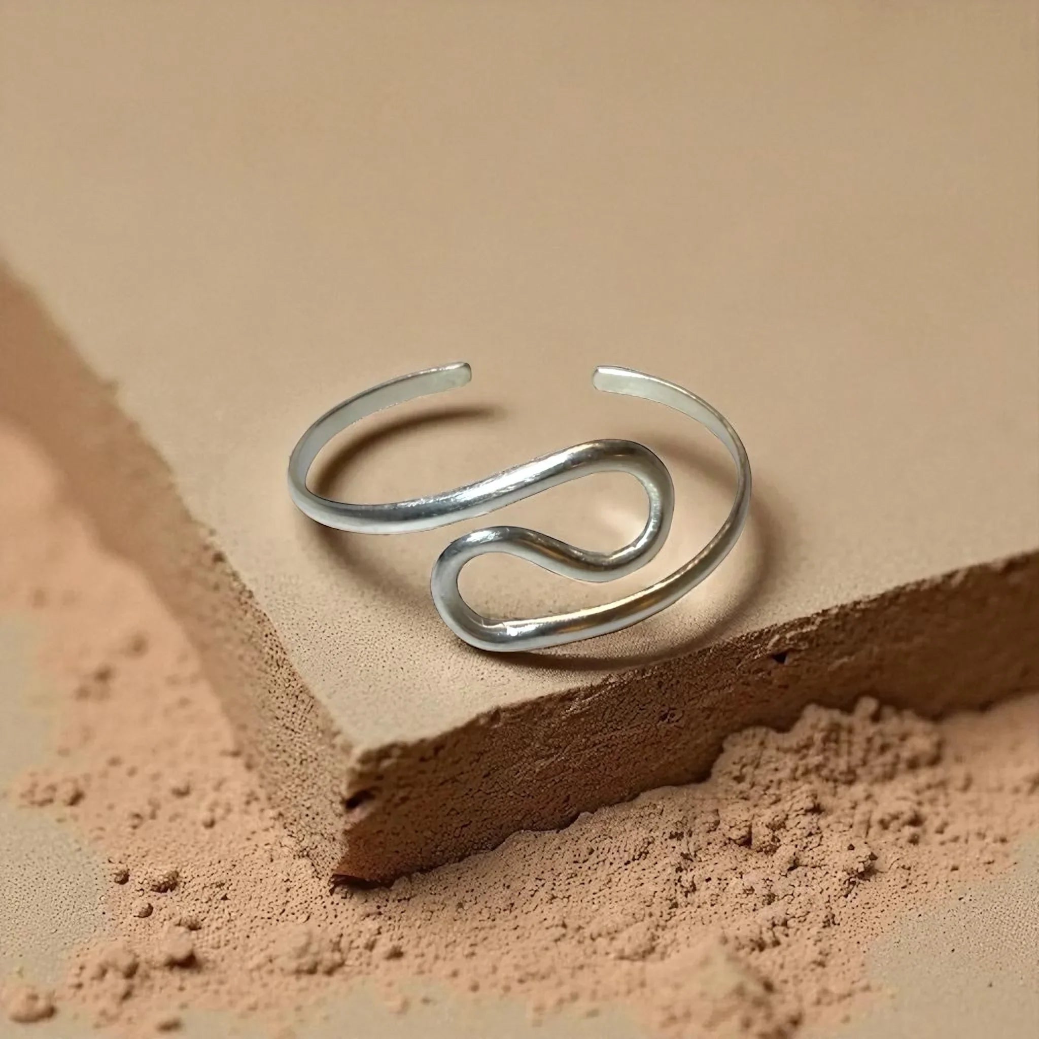 Silver open ring on a textured beige surface