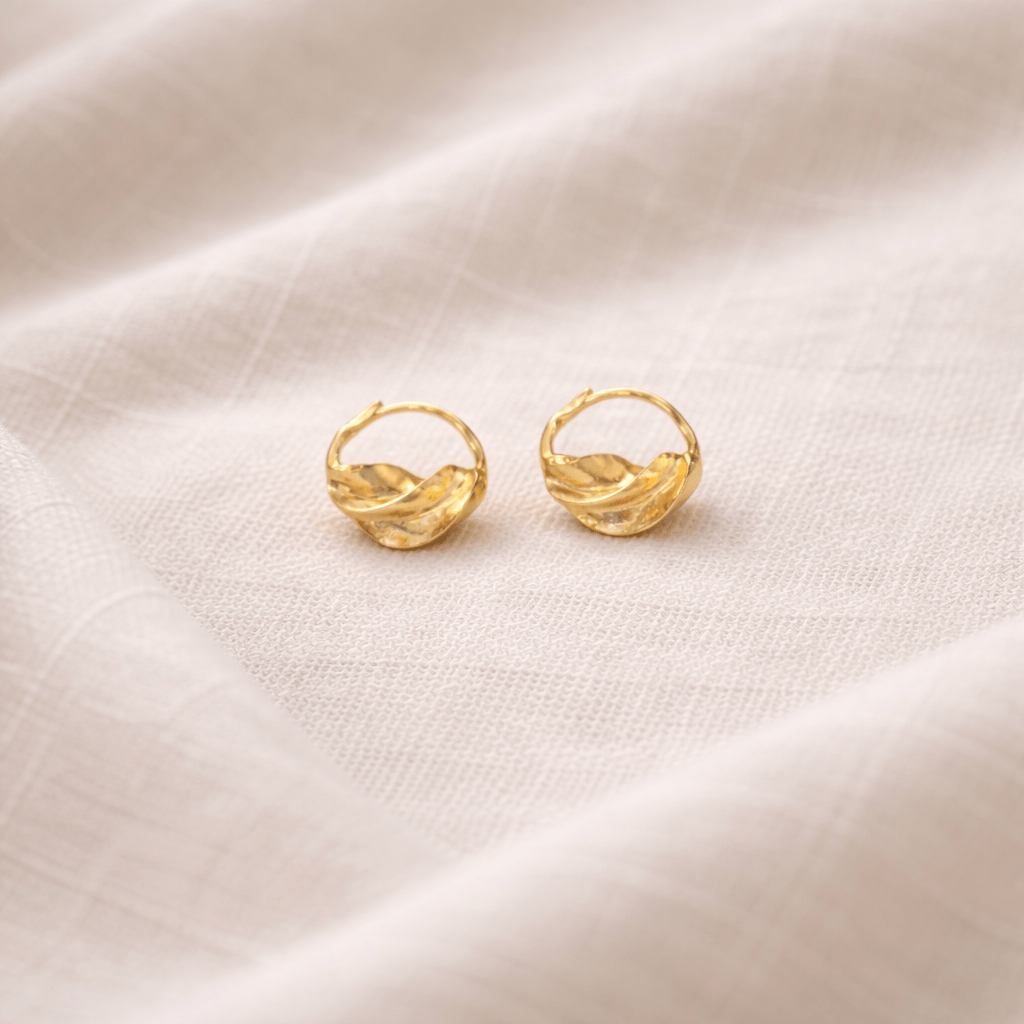 Gold hoop earrings on a beige fabric background