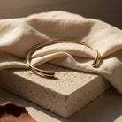 Gold bracelet on a textured beige surface