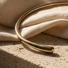 Gold bracelet on a textured beige surface