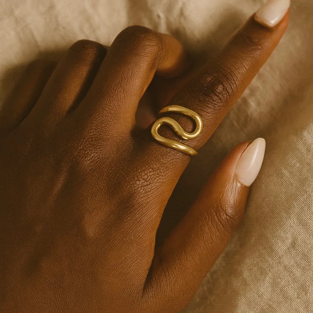 Gold ring on a person's finger with a neutral background