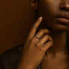 Close-up of a person's hand with a ring on a brown background
