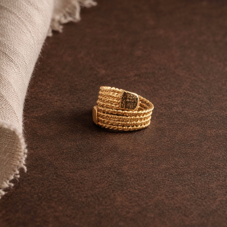 Gold ring with a dark stone on a brown textured surface