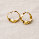 Gold hoop earrings on a beige fabric background