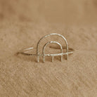 Silver ring with arch design on a beige fabric background