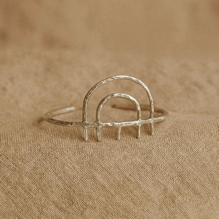 Silver ring with arch design on a beige fabric background