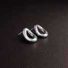 Pair of silver earrings on a dark brown surface