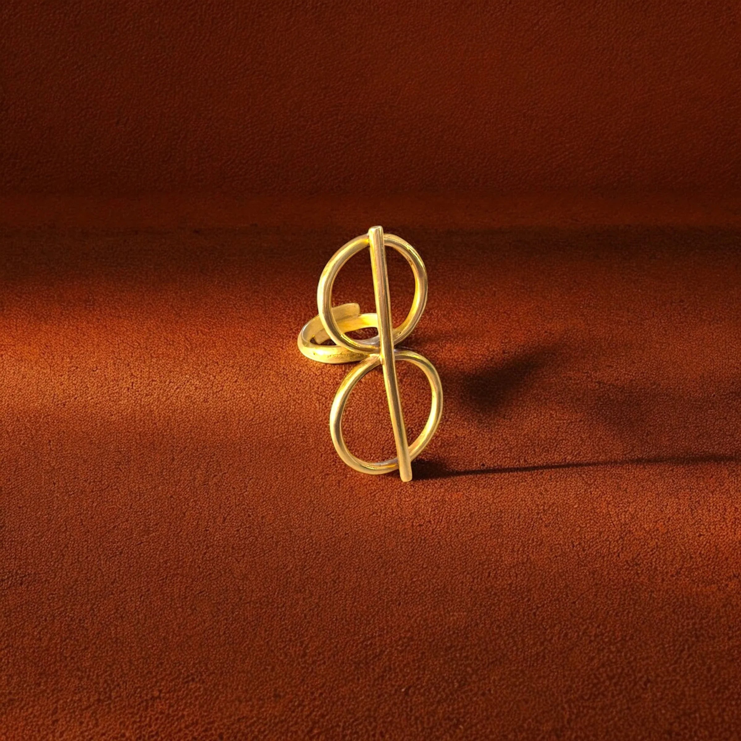 Gold ring with a unique design on a brown fabric background