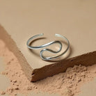 Silver open ring on a textured beige surface