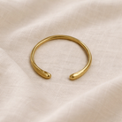 Gold bracelet on a beige fabric background