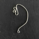 Silver wire earring on a black textured background
